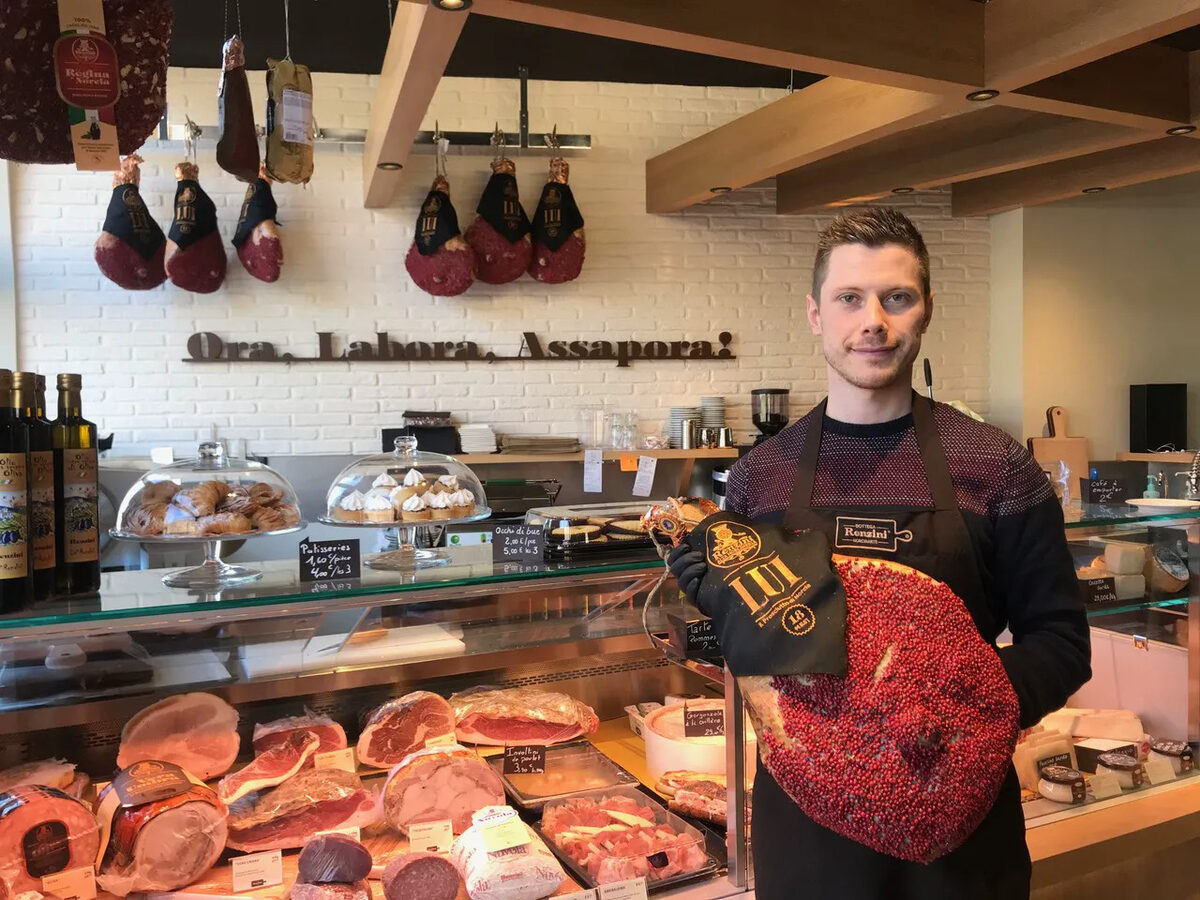 Julien Febvre derrière le comptoir de la Bottega Renzini, un jambon Renzini dans les bras. Photo Pokaa